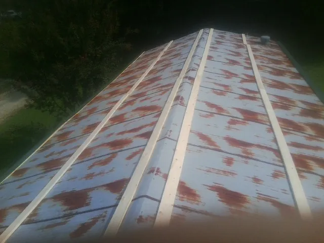 Rusted metal roof panels with new wood purlins before replacement — Storm Damage Roof Repair in Davenport by Roofing Brothers
